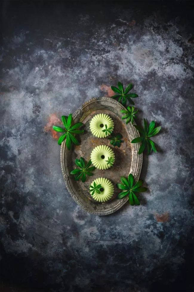 Ich weiß noch wie enttäuscht ich war, als ich das erste Mal ein Dessert mit natürlichem Waldmeister bei Freunden gegessen habe. Ich war bis dahin nur den chemischen Waldmeistergeschmack von Wackelpudding, Sirup und Co. gewöhnt. Mittlerweile liebe ich den natürlichen, süßen Geschmack von Waldmeister sehr und kann nicht einmal beschreiben, nach was er eigentlich schmeckt. Ist auch egal, lecker muss es sein. Aber ich hab auch munklen gehört, dass Waldmeister sehr betörend sein soll. Dieses Jahr wächst der Waldmeister bei uns im Wintergarten und ich musste mich erst einmal informieren, wie der gute Herr Meister gerne wohnen und geerntet werden will. Viel wichtiger war aber, wie er zubereitet werden muss. Gepflückt verwelkt Waldmeister ziemlich schnell, was dem Geschmack zu Gute kommt, denn erst angewelkt verströmt er seinen leckeren Duft. Verrückt.