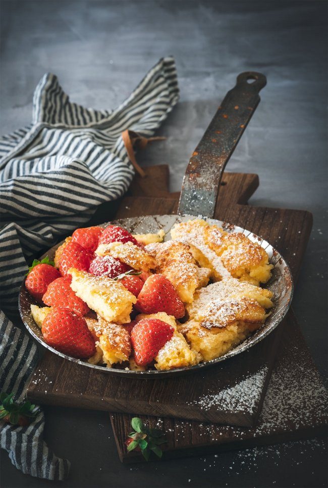 Du magst Grießpudding und Kaiserschmarren? Dann mach Dir eine Pfanne voller Grießschmarrn. Warm aus dem Ofen ein Hammer! So ein richtiger Kaiserschmarrn oder Kaiserschmarren (ich hab noch nicht herausgefunden ob mit „e“ oder ohne „e“ und nehme die vom Duden empfohlene Schreibweise), ist und bleibt einfach was richtig Tolles. Die Version mit Grieß kannte ich selber noch nicht und hab diese in einer Zeitschrift gesehen und das Rezept wanderte direkt auf meine „to do“ Liste. Meistens habe ich nämlich auch immer alle Zutaten im Haus, um die manchmal plötzlich auftretende Kaiserschmarren-Lust, zu befriedigen. Und ich war wirklich überrascht wie lecker ein Kaiserschmarren mit Grieß sein kann. Das wird jetzt öfter so gemacht. Heute mal mit frischen Erdbeeren und viel Puderzucker. Ansonsten gerne auch mal mit Fruchtsirup und Vanillesoße.