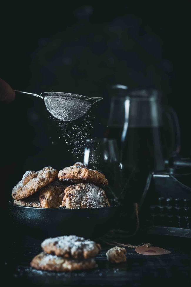 Stollen Cookies Stollen Kekse Super einfache, besonders leckere und perfekt süße Stollen-Kekse. Die Kekse bestehen aus braunem Zucker und wärmendem Rum (für die Kinderversion kann man natürlich auch Orangensaft nehmen). Sie sind weich und buttrig und haben einen leckeren Marzipankern. Jeder Keks wird dann noch liebevoll mit Puderzucker bestäubt. 15 große Kekse 40 g getrocknete Cranberrys 40 g Rosinen Abgeriebene Schale 1 Orange 4 TL Rum 60 g Marzipan 75 g Mandeln 125 g Butter, Zimmertemperatur 100 g Zucker 75 g brauner Zucker 1 Ei 225 g Mehl 1 TL Zimt Muskatnuss Koriander, gemahlen Ingwer, gemahlen 10 Tropfen Bittermandel-Aroma Puderzucker Cranberrys, Rosinen und Orangenschale mit dem Rum in einen kleinen Topf geben und 5 Minuten köcheln lassen, dann zur Seite stellen Marzipan zu 15 Kugeln formen und bis zur weiteren Verarbeitung in die Gefriertruhe geben Backofen auf 200 Grad Ober-Unterhitze vorheizen Mandeln im Backofen 5 Minuten rösten, dann grob hacken Backofen ausschalten Butter, Zucker und braunen Zucker schaumig aufschlagen Ei, Bittermandel-Aroma und Mehl unterrühren Eingelegte Früchte inkl. Rum und gehackte Mandeln zugeben und unterrühren Teig zu 15 Kugeln formen und jeweils eine Marzipankugel in die Mitte drücken Teigkugeln mit der Marzipankugel nach oben auf ein mit Backpapier ausgelegtem Backblech legen und 1 Stunde ruhen lassen Backofen auf 180 Grad Ober-Unterhitze vorheizen Kekse 10-12 Minuten backen Vor dem Servieren mit Puderzucker bestäuben