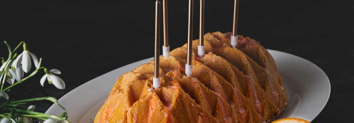 Ich musste noch einmal bei den Blutorangen zuschlagen, bis die Saison dann bald vollständig vorbei ist. Der griechische Joghurt im Kuchen, in Kombination mit der Blutorange, lässt ihn fast wie ein Softeis schmecken. Ich habe noch ein paar Kerzen auf den Kuchen gepackt. Sah irgendwie besser aus. Zu feiern gibt es ja eh ständig etwas.