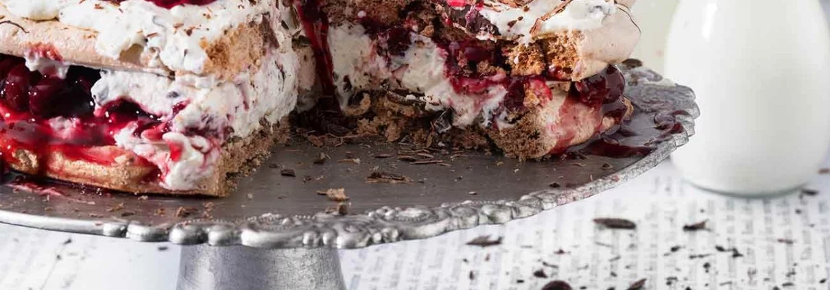 Schwarzwälder Kirsch-Baiser-Kuchen Black Forest cherry meringue cake Schwarzwälder Kirsch bleibt und ist einfach ein richtig guter Kuchenklassiker. Ich mag manchmal einfach keine Tortenböden backen, so dass ich kurzerhand die Biskuitböden gegen leckere Schokoladenbaisers ersetzt habe. Geht unheimlich flott und ist ab sofort unsere Lieblingsversion der Schwarzwälder Kirschtorte. 5 Eiweiß 1 TL Essig 200 g Zucker 2 TL Speisestärke 3 EL Kakaopulver 200 g Zartbitterkuvertüre 600 g Schlagsahne 3 Blatt Gelatine 600 g Sauerkirschen (Glas) 50 g brauner Zucker 2 Pck. Vanillezucker 50 ml Kirschwasser 6 TL Sofortgelatinepulver (weniger als 1 Pck) Backofen auf 140 Grad Ober-Unterhitze vorheizen und zwei Backbleche mit Backpapier auslegen Eiweiße mit dem Essig steif schlagen Zucker mit der Speisestärke vermengen und nach und nach einrieseln lassen Kakaopulver unterheben Auf den Backpapieren einen Teller mit 22 cm Durchmesser legen und nachzeichnen Eiweißmasse in einen Spritzbeutel geben und die beiden Kreise ausspritzen Die Böden ca. 1,5 Stunden im Backofen backen, danach auskühlen lassen 100 g Zartbitterkuvertüre über einem Wasserbad schmelzen lassen und die Baiserböden damit einpinseln, trocknen lassen Blattgelatine in kaltem Wasser einweichen Sauerkirschen abseihen und 200 ml Saft auffangen 150 ml Saft mit dem braunen Zucker und den Kirschen verrühren, restlichen Saft mit der Speisestärke verrühren Kirschen mit Saft in einen Topf geben und aufkochen lassen und mit der Speisestärkemischung binden Kirschkompott abkühlen lassen Sahne, Vanillezucker, Kirschwasser und Sofortgelatinepulver steif schlagen Restliche Kuvertüre raspeln und 2/3 unter die Sahne heben Einen Baiserboden mit Sahne und Kirschkompott bestreichen, zweiten Boden auflegen und restliche Sahne darauf verteilen Restlichen Kompott und Schokoraspeln darauf verteilen TIPP: Wer das Kirschwasser weglassen will, kann die Sahne auch mit Sahnesteif steif schlagen und benötigt keine Sofortgelatine