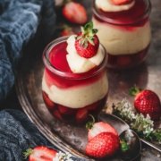 Götterspeise mit Orangen-Vanillepudding und Erdbeeren Jelly with orange custard and strawberries Jetzt wird es fruchtig im Glas: Himbeer, Erdbeer und Orange! Den Wunsch „ich möchte mal wieder Götterspeise essen“ habe ich erfüllt. Ich finde Götterspeise ehrlich gesagt ja ziemlich langweilig, aber in dieser Kombination finde ich sie richtig klasse. 4 Portionen 1 Beutel Himbeer Instant Götterspeisenpulver für 500 ml Wasser 1 Pck. Vanille-Puddingpulver zum Kochen 500 ml Orangensaft 100 g Zucker 300 ml Schlagsahne 250 g Erdbeeren, gewürfelt Puddingpulver mit dem Zucker und 6 EL Orangensaft verrühren Restlichen Saft aufkochen, angerührtes Puddingpulver zugeben und aufkochen lassen Eine Minute köcheln lassen, auskühlen lassen, dabei ab und zu umrühren 500 ml kochendes Wasser mit dem Instant Götterspeisenpulver verrühren und ca. die Hälfte der Flüssigkeit auf 4 Gläser aufteilen Erdbeerwürfel zugeben und kalt stellen 2/3 der Orangen-Vanillepudding auf die Gläser verteilen, danach die restliche Götterspeise darüber gießen, gefolgt von dem restlichen Pudding Alles im Kühlschrank fest werden lassen
