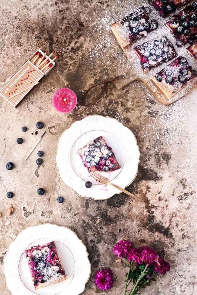 Gestern habe ich diesen buttrigen Hefekuchen gebacken. Die beiden ersten Schnittchen sind noch lauwarm in den Mund gewandert. So lecker. Süß, einfach und lecker. Ein leichter und fluffiger Hefeteig mit fruchtigen Blaubeeren und knackigen Cashewkernen. Der perfekte Beerenkuchen für alle Gelegenheiten.