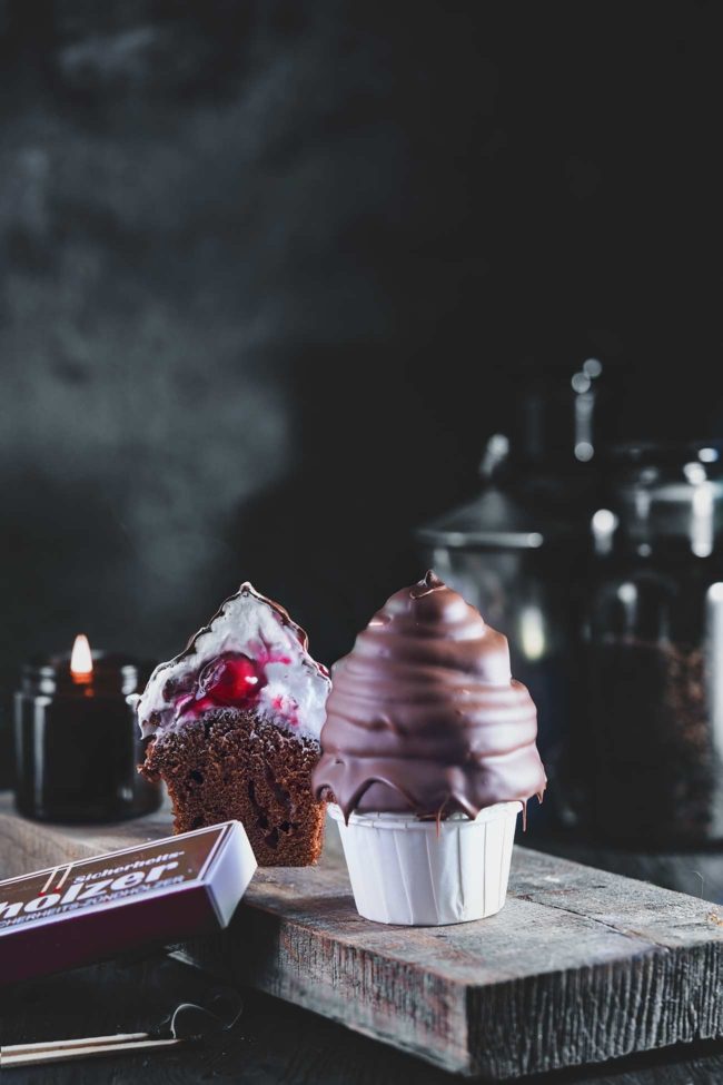 Ich steh gerade auf Schokoküsse. Deshalb bekommen die Schokoladen Cupcakes eine große Haube Schaumkuss-Masse, die natürlich in Schokolade getaucht wird. Richtige „High Hat“ Cupcakes. Und wenn man reinbeißt und als Überraschung ein paar Kirschen zum Vorschein kommen, ist das einfach richtig lecker.