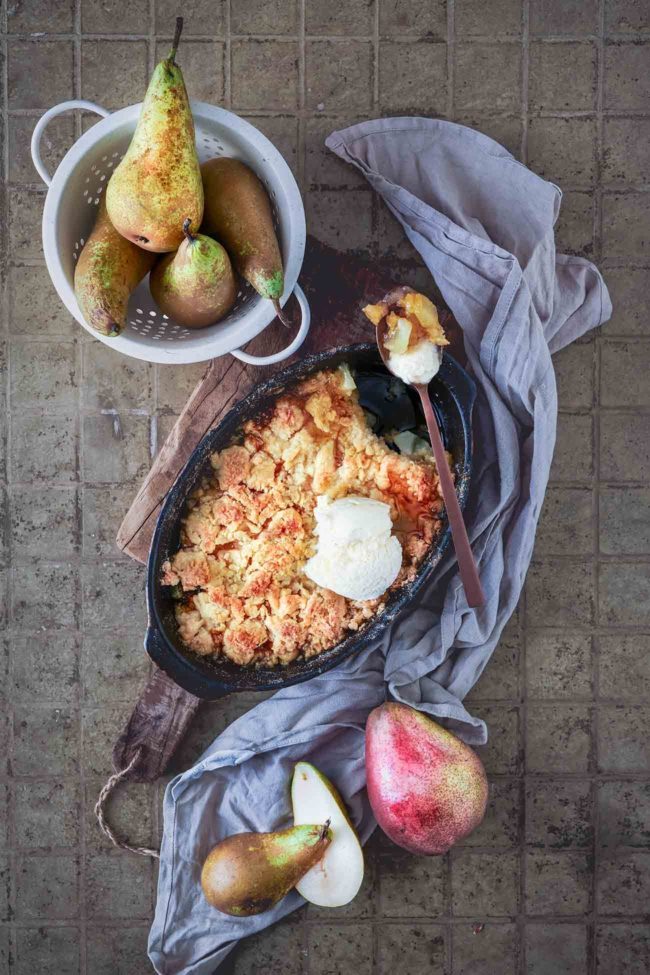 Eine Auflaufform vollgestopft mit Birnen, Sirup und einer Menge Butterstreuseln obendrauf. Jeder Bissen ein köstliches Augenrollen und voller Geschmack. Einfach ein saftiges Dessert mit einem Hauch von Vanille. Ich liebe es direkt aus dem Ofen mit etwas Vanilleeis.