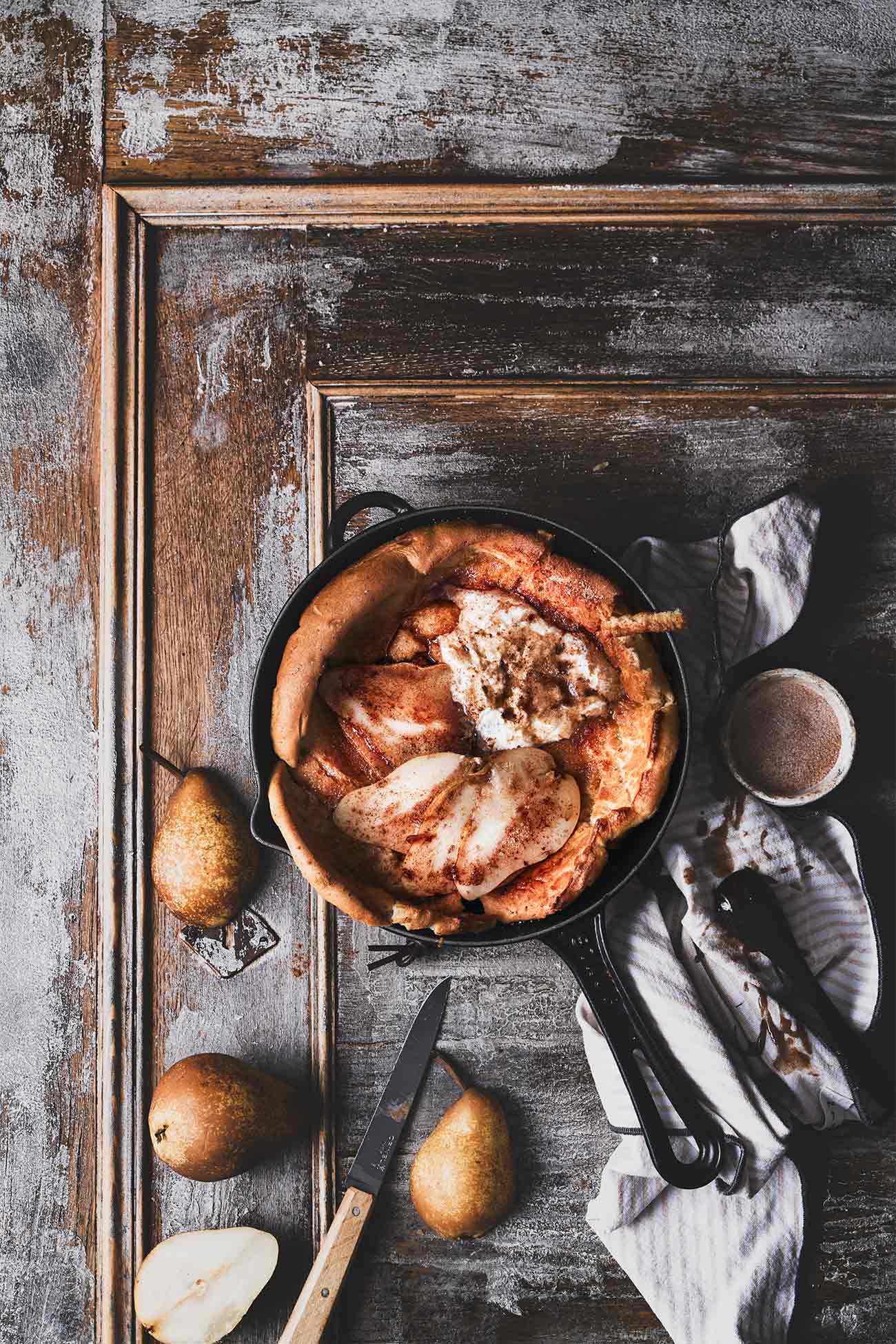 Ein Dutch Baby passt zum Frühstück genauso gut, wie auch zum Mittagessen. Eigentlich geht er immer. Dieser Ofenpfannkuchen hat noch ein Geheimnis, denn unter ihn befinden sich noch karamellisierte Birnenscheiben mit brauner Butter. Getoppt wird das Ganze dann mit Sahne und Zimtbutter. Ich habe schon viele Dutch Babys gemacht, aber dieser ist mir der Allerliebste. Das ganze Geheimnis dieses Ofen-Pfannkuchens ist, dass die Pfanne vorher schon im Ofen erhitzt werden muss, damit der Pfannkuchenteig so schön aufpufft. Warum das so ist, kann ich nicht erklären, aber was du wirklich wissen musst, ist, dass es einfach magisch ist. 