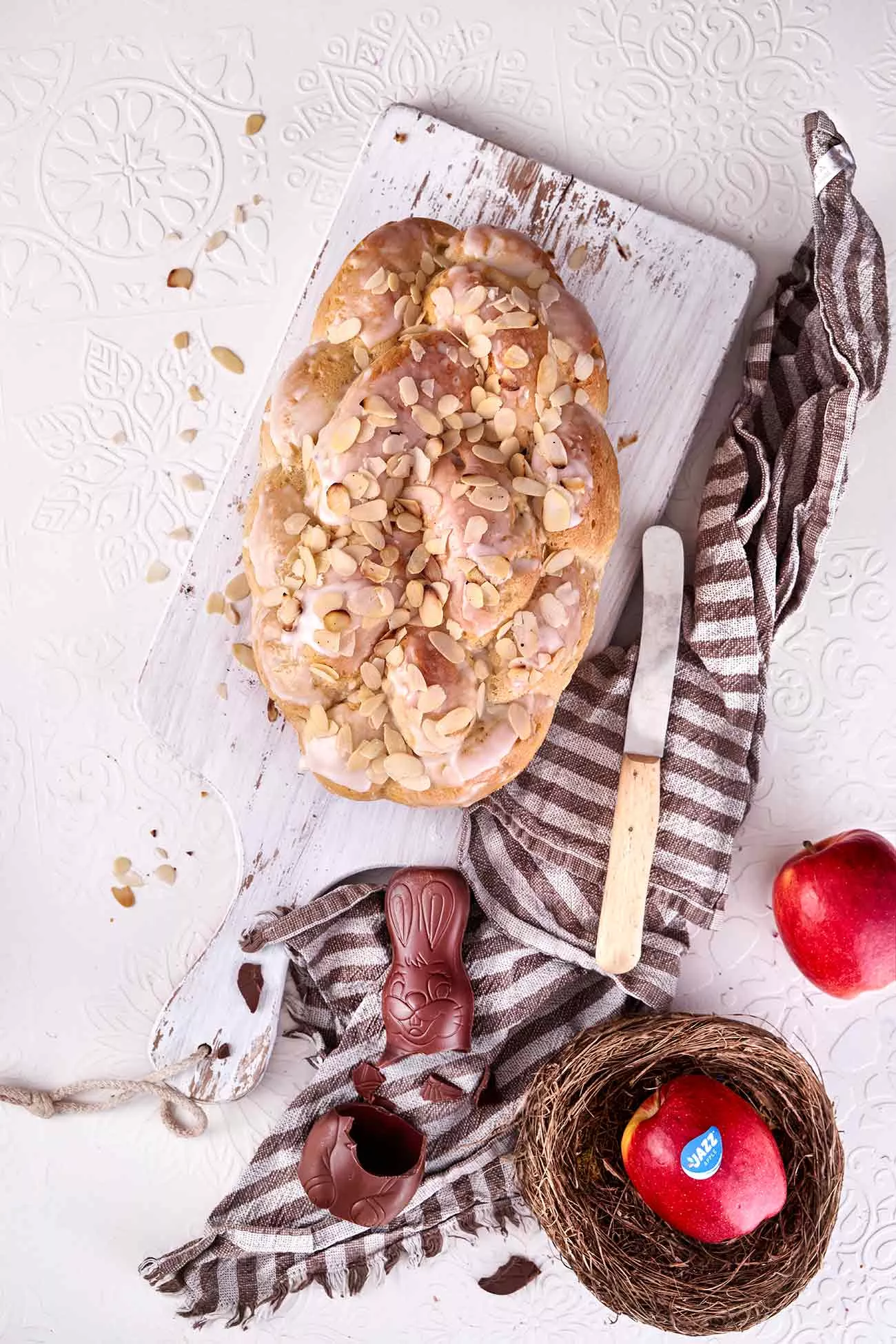 Ohne Osterzopf ist es kein richtiges Osterfest. Ich mag ihn am liebsten mit Zuckerguss und Mandelblättchen. Und da mir der gekaufte meist schon am nächsten Tag nicht mehr schmeckt, wird halt selbst gebacken. Aber jetzt kommt der Osterkranz 2.0, denn ich habe 2 geriebene JAZZ™ Äpfel unter den Teig geknetet. Die leichte süße der knackigen Äpfel und die gleichzeitig milde Säure passen einfach perfekt zu dem fluffigen Teig und der zitronigen Glasur.  Ok, ein wenig habe ich geschummelt, denn ich bin nicht ziemlich gut im Flechten. Weder Haare noch Teig. Ich habe mir einfach eine Backform im „Zopf-Style“ gekauft.  Das Rezept findest du auf dem Blog, in der Version ohne Backform. Also ran ans flechten. 