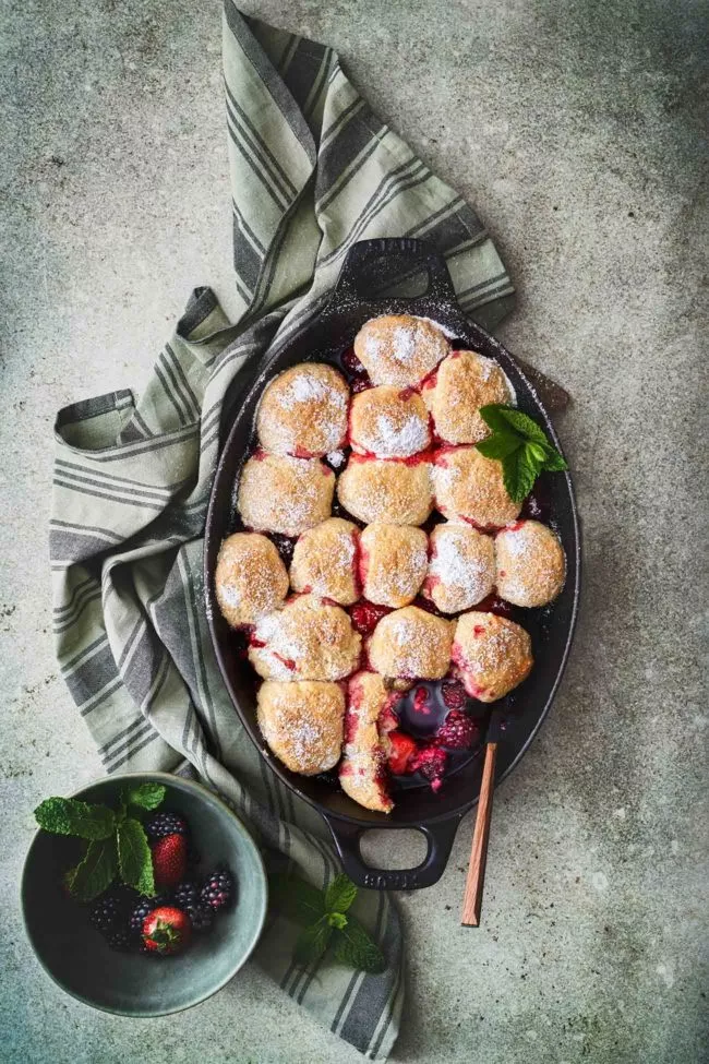 Was bei mir mal als Resteverwertung von übrig gebliebenen Erdbeeren und angebrochenen TK-Beeren angedacht war, hat sich mittlerweile als Lieblingsdessert etabliert. Der Teig ist in 5 Minuten geknetet und der Ofen sorgt dafür, dass die Beeren Saft abgegeben. Auf den Tisch stellen und löffeln. So lecker.
