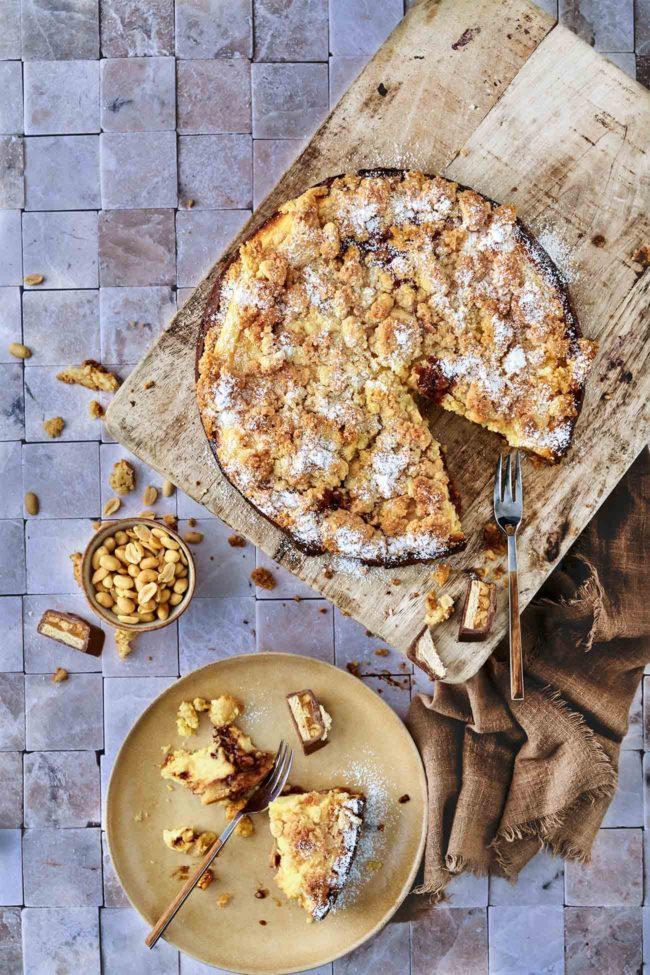 Dieser Erdnuss-Käsekuchen ist reichhaltig und köstlich und erfordert so wenig Aufwand. Cremig geschlagener Quark mit Erdnüssen und kleinen Schokoriegel-Stücken. Dieser Käsekuchen ist leicht, cremig, luftig, leicht butterig, leicht gesüßt und perfekt mit etwas Erdbeerkonfitüre angereichert.