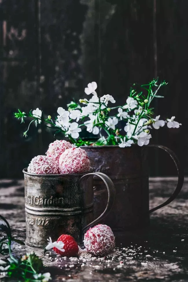 Sommer Kokos-Himbeerkugeln aus weißer Schokolade White chocolate summer coconut and raspberry balls Wenn ich mir diese kleinen Sommerkugeln machen, habe ich Bilder von weißen großen Hüten, weißen leichten Sommerkleidern, blauem Meer, weißen Stränden und lächelnden Gesichtern im Kopf. Wenn ich mich dann so umsehe, schmecken die schnell gemachten Kokoskugeln mit Mandelkern auch ohne Hut, mit Jogginganzug, umgeben von grünen, saftigen Wiesen auch sehr gut. Und lächeln kann ich auch.