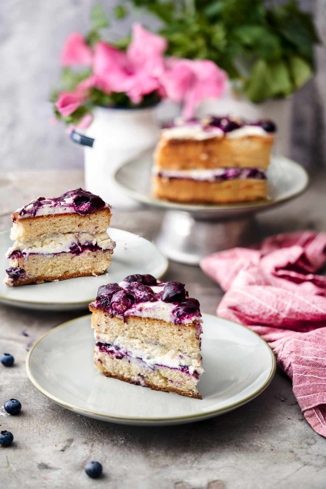 Heidelbeer-Torte Berry pie Ich mag diese einfachen Torten einfach am liebsten. Wenig Gedöns, aber eine Menge an Mascarponecreme und süßen Beeren. Ein fluffiger Teig. Alles stapeln. Fertig. 200 g Butter, weich 180 g Zucker 1 Pck. Vanillezucker 4 Eier 180 g Mehl 1 TL Backpulver 100 g gemahlene Mandeln 100 g Sauerrahm 300 g TK-Heidelbeeren Abgeriebene Schale ½ Zitrone 2 TL Speisestärke 200 ml Sahne 700 g Mascarpone 1 TL Vanilleextrakt 5 EL Cassis-Likör (optional) Backofen auf 180 Grad Ober-Unterhitze vorheizen und die Springform einfetten, 200 g Butter mit 120 g Zucker und Vanillezucker schaumig aufschlagen, Eier nach und nach unterrühren. Mehl, Backpulver und gemahlene Mandeln vermengen und nach und nach unterrühren. Sauerrahm unterrühren. Teig in die Form füllen und 60 Minuten backen, herausnehmen und abkühlen lassen. Heidelbeeren mit Zitronenschale, 50 g Zucker und 5 EL Wasser 5 Minuten köcheln lassen, Heidelbeeren mit einer Gabel etwas zerdrücken. Speisestärke mit 1 EL Wasser verrühren und in das Heidelbeerkompott rühren und 5 Minuten köcheln lassen., dann abkühlen lassen. Sahne und 10 g Zucker steif schlagen. Mascarpone mit Vanilleextrakt und Cassis verrühren. Sahne unterheben. Kuchen quer halbieren. Die Hälfte vom Beerenkompott auf einen Boden verteilen, gefolgt von der Hälfte der Mascarponecreme. Zweiten Boden auflegen. Mascarponecreme darauf verteilen, gefolgt vom restlichen Kompott.