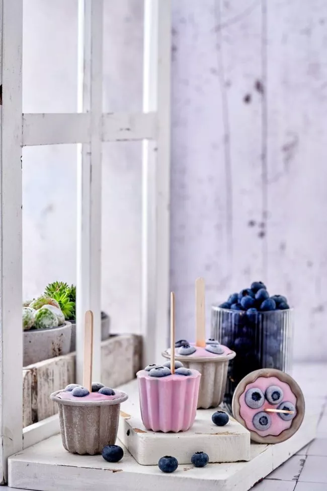 Noch nie war Joghurt machen so einfach. Mit dem Joghurtzubereiter EasiYo, den es bereits ab 29,99 Euro inkl. Joghurtpulver für 2 kg gibt, ist es richtig einfach, sich seinen Lieblingsjoghurt zuzubereiten. Das Schwierigste ist, sich zwischen den leckeren Geschmacksrichtungen zu entscheiden. Gerade im Sommer essen wir viel Joghurt. Zum Frühstück mit Obst, tagsüber gern als Frozen Joghurt und abends auch gerne als leckeres Eis am Stiel. Die Kombinationsmöglichkeiten sind unzählig. Wie das geht? Mit Wasser aufgießen, schütteln und den Rest über Nacht den Lebendkulturen überlassen. Dann nur noch kühlen und fertig ist ein köstlicher Joghurt Wir lieben besonders den Naturjoghurt nach griechischer Art ohne zusätzlichen Zuckerzusatz. Für Alle, die einen Joghurt gesucht haben, um Frozen Joghurt herzustellen, hat ihn jetzt gefunden. Denn der schmeckt wie bei den angesagtesten Frozen Joghurt Shops. Für die Popsicles habe ich mich für den Blaubeer-Joghurt entschieden. Einfach Joghurt einen Tag vorher zubereiten, in Muffinförmchen oder Kuchenförmchen füllen, Heidelbeeren darauf verteilen und ein Holzstäbchen mittig in die Form stellen und einfrieren.