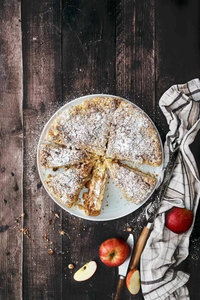 Ich freue mich so sehr auf die anstehende, regionale Apfelsaison, dass ich nicht mehr abwarten konnte und diesen saftigen Kuchen, der mit einer Skyr-Schmand Füllung überrascht, backen musste. Dazu Mandelstreusel und eine dicke Schicht aus Puderzucker. Ein Apfeltraum.