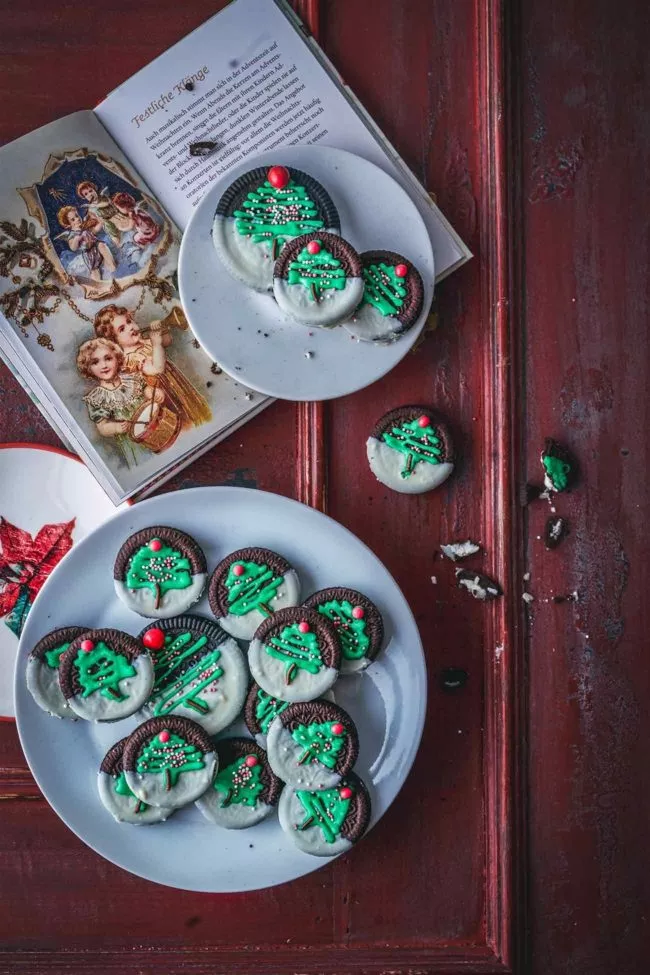 Hach, was finde ich die Kekse schön. Und Oreo-Fans werden die schnell gemachten Weihnachtskekse lieben. Oreos zur Hälfte in weißer Schokolade tunken, fest werden lassen und mit grüner Zuckerglasur einen Tannenbaum aufspritzen, mit Streuseln verzieren und einen Schokostreusel als Baumstamm verwenden. Auf dem Blog verrate ich euch noch mein Lieblings-Royal Icing-Rezept. Wenn es nur um wenig Verzierung von Keksen geht, reicht etwas Lebensmittelfarbe, 250 g Puderzucker, ein Eiweiß, eine Prise Salz und etwas Wasser. Alle Zutaten mit dem elektrischen Handrührgerät auf niedriger Stufe (wichtig) zu einer dickflüssigen Masse verrühren. Wenn du richtig loslegen willst und Kekse richtig schön verzieren möchtest, dann kommt hier jetzt das weltbeste Royal Icing Rezept.