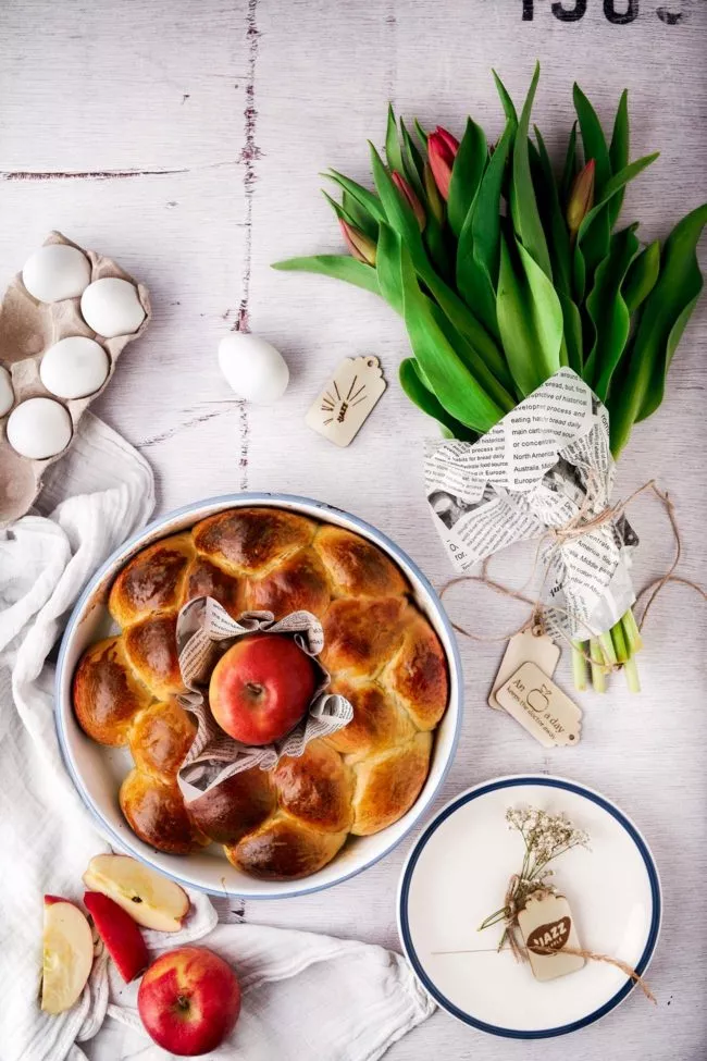 Ohne Osterkranz kein Ostern. Meiner ist dieses Jahr mit geriebenen JAZZ™ Äpfeln, die dem ganzen einen knackig und spritzig-süßen Geschmack geben. Der Osterkranz ist eine unglaublich schöne alte Tradition, als Form des ewigen Lebens. Traditionell werden bunt bemalte, gekochte Eier in die Mitte gesteckt. Ihr wisst ja, wie ich den JAZZ™ Apfel feiere, daher kommt er, anstelle der Eier, in die Mitte. Und da der JAZZ™ Apfel eine so tolle rote natürliche Farbe hat, spare ich mir das Färben. In dem Sinne: habt eine tolle Osterzeit