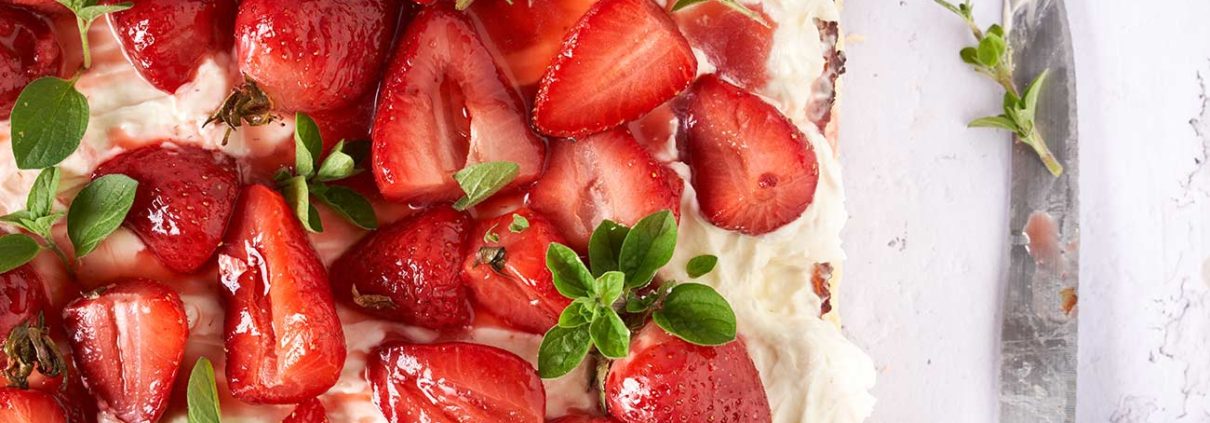 Der Blechkuchen mit gerösteten Erdbeeren lässt mir noch beim Schreiben das Wasser im Mund zusammenlaufen. Wenn du die Erdbeeren mit Honig und Thymian röstest, entsteht ein köstlicher Erdbeersirup, der den Kuchen perfekt ergänzt. Dieser Blechkuchen besteht aus drei unwiderstehlichen Schichten, die jeden Bissen zu einem Genuss machen. Die erste Schicht ist der Boden, mit leichtem Orangengeschmack.Dieser Boden bildet die perfekte Grundlage für den Kuchen und bietet einen angenehmen Kontrast zu den cremigen Toppings. Die zweite Schicht ist die verlockende Käsekuchenfüllung mit Frischkäse und cremigen Ricotta, die im Ofen gebacken wird. Die dritte Schicht ist eine Creme aus Mascarpone und frischer Sahne und den gerösteten Honig-Erdbeeren. Der Honig karamellisiert leicht und verleiht den Erdbeeren eine süße Note, während der Thymian einen subtilen Hauch von Kräutern hinzufügt. Verteile die gerösteten Erdbeeren auf dem gebackenen Käsekuchen und beträufle ohn mit dem entstandenen Erdbeersirup.