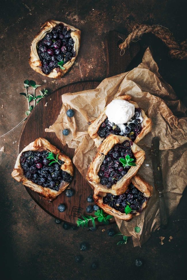 Dieses Rezept ist einfach unwiderstehlich! Mit nur wenigen Zutaten, die schnell und einfach zusammengemischt werden können, sind diese kleinen Küchlein aus Blätterteig ein echtes Highlight. Das Geheimnis dieser leckeren Küchlein liegt in der Kombination aus saftigen Heidelbeeren, Vanille und erfrischender Zitrone und Thymian. Wenn die Heidelbeeren im Ofen zerplatzen, entsteht ein köstlicher Saft, der die kleinen Küchlein saftig und fruchtig macht.