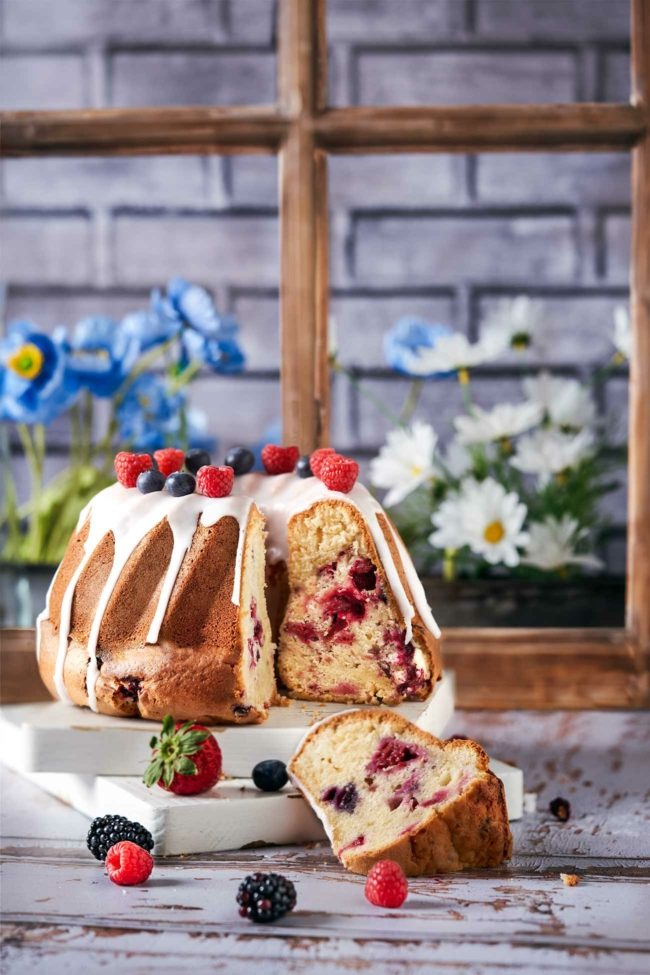 Beeren Gugelhupf mit Glasur vor einem Küchenfenster