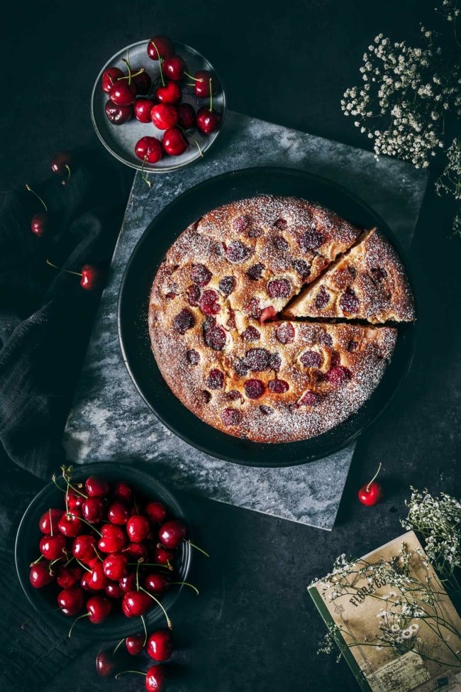 Kirschkuchen auf einem Tisch mit Kirschen drumherum