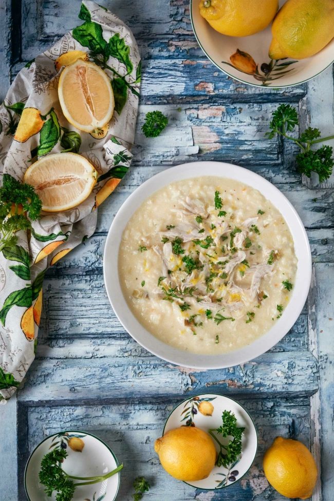 Sommersuppe mit Zitronen und Hähnchenfleisch und Reis auf einem blauen Tisch, dekoriert mit frischen Zitronen